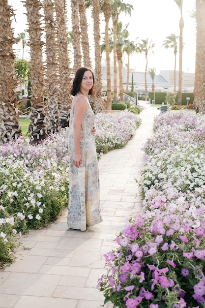 Donna in abito lungo tra i fiori e le palme