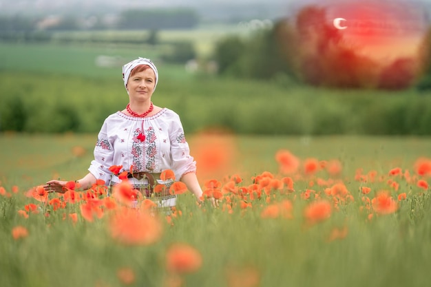 Donna in abito nazionale ucraino su un campo di papaveri in fiore