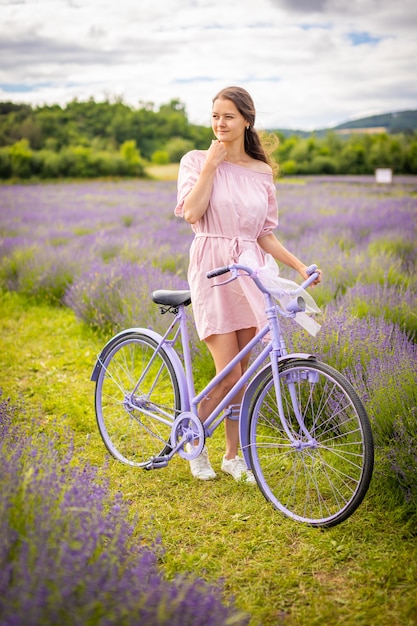 Donna in abito rosa con bicicletta retrò nel campo di lavanda repubblica ceca