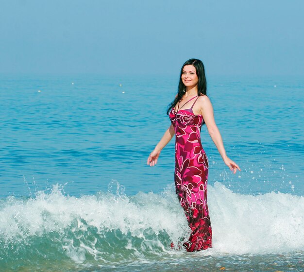 Donna in abito rosa sulla spiaggia del mare