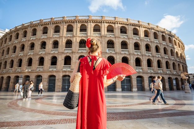 Donna in abito rosso con lo spagnolo ventaglio stnading torna di fronte all'anfiteatro dell'arena nella città di Valencia, Spagna