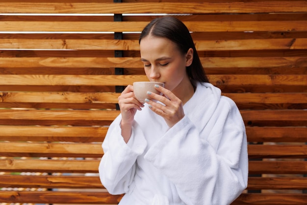 Donna in accappatoio che beve tè dopo i trattamenti termali