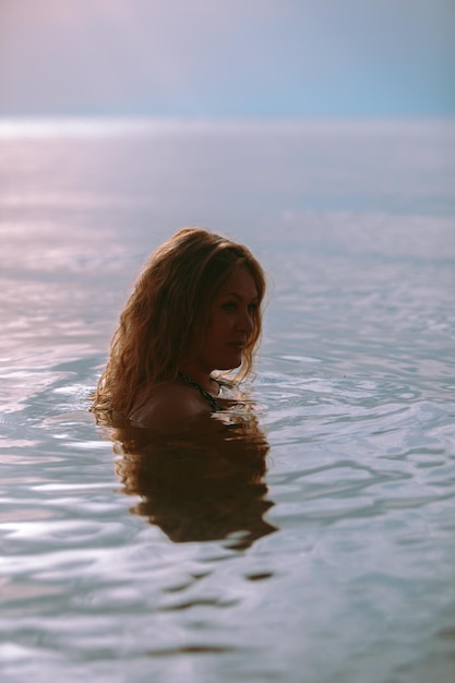 Donna in acqua di mare al tramonto