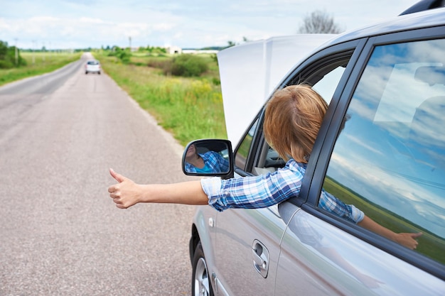 Donna in attesa di aiuto e pollici dall'auto