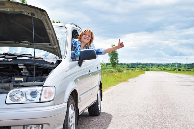 Donna in attesa di aiuto e pollici dall'auto