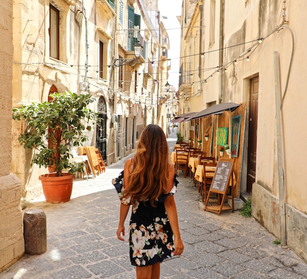 Donna in bellissimo abito fiorito camminando per le strade di Siracusa, Sicilia