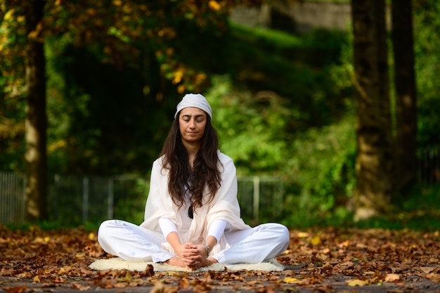 Donna in bianco nella sosta di autunno mentre si fa yoga