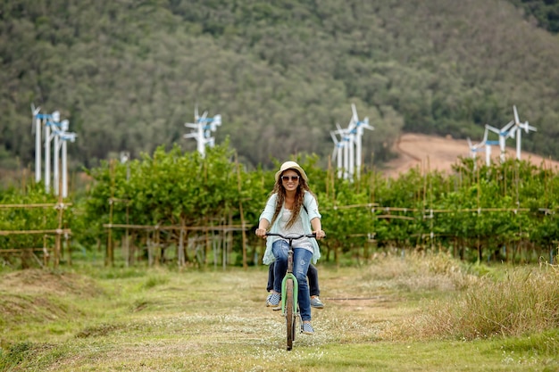 Donna in bicicletta in campo con turbine eoliche in background