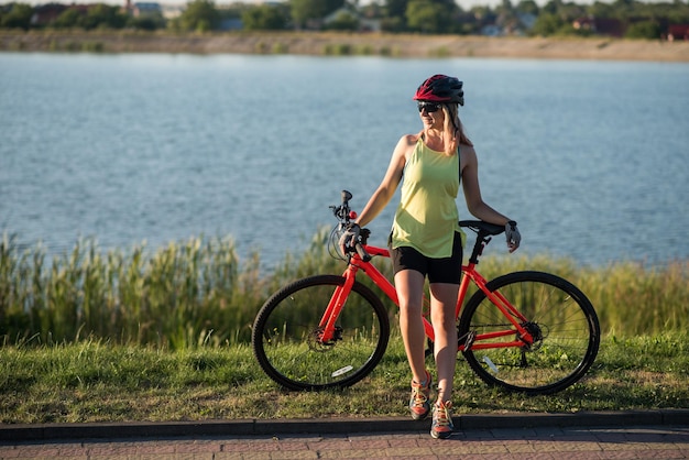 Donna in bicicletta sullo sfondo dell'acqua del lago nel parco