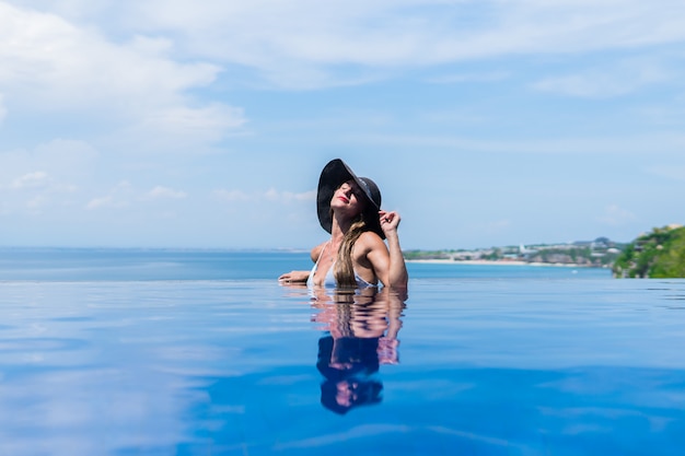 donna in bikini e un cappello è rilassante in piscina