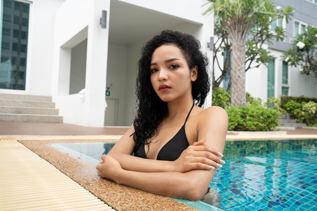 Donna in bikini in piscina Piscina abbronzata corpo snello e formoso Ragazza che si gode le vacanze di viaggio nel lussuoso bungalow sull'acqua del resort