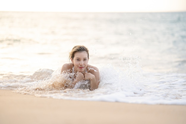 Donna in bikini sdraiata sulla spiaggia di sabbia in acqua.