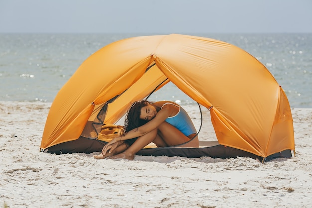 Donna in bikini sulla spiaggia in tenda