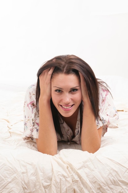 Donna in breve tuta colorata sdraiata sul letto bianco