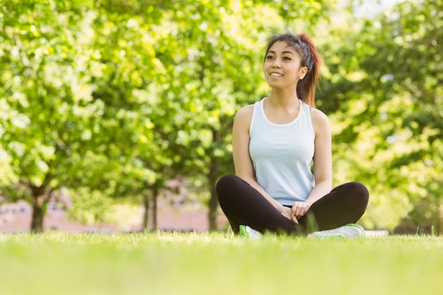 Donna in buona salute che si siede sull&#39;erba nel parco