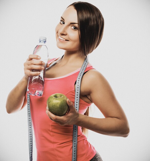 Donna in buona salute con acqua e mela dieta sorridente isolato su bianco