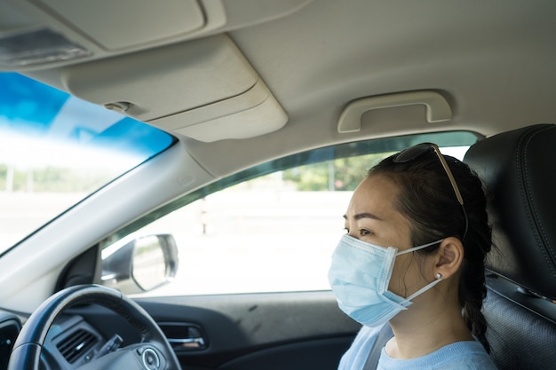 Donna in buona salute con maschera protettiva che guida l'auto