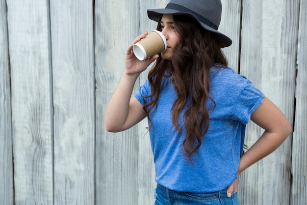 Donna in caffè bevente superiore blu dalla tazza eliminabile