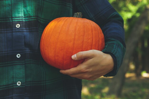 Donna in camicia a scacchi tenere zucca all'aperto