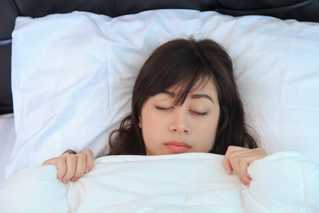 donna in camicia bianca che dorme sulla sua camera da letto. concetto per sano.