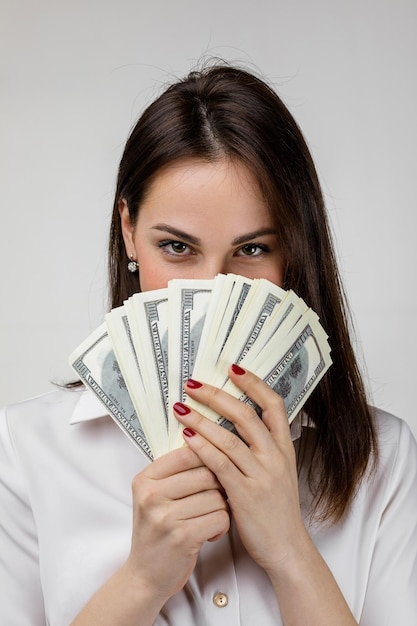 Donna in camicia bianca che si nasconde dietro un mucchio di banconote