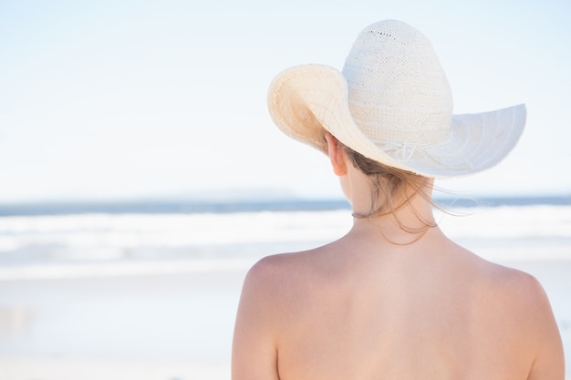Donna in cappellino da sole che guarda fuori al mare