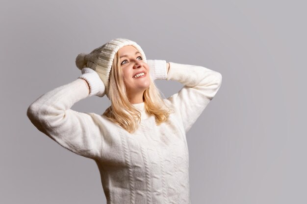 Donna in cappello bianco con bubo e guanti sorride tiene il suo cappello con le mani