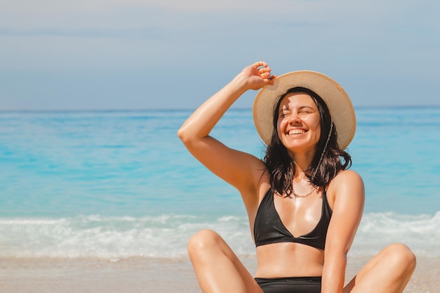 Donna in cappello bianco e costume da bagno nero nelle vacanze estive dell'acqua di mare blu