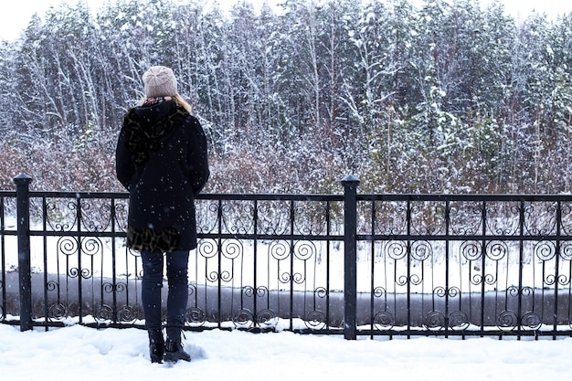 donna in cappotto nero in inverno da sola sull'argine