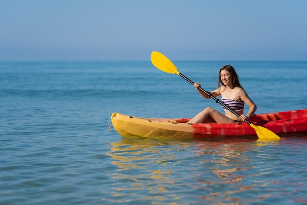 Donna in costume da bagno che rema un kayak in mare