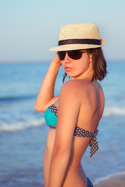 donna in costume da bagno e cappello per il sole in spiaggia