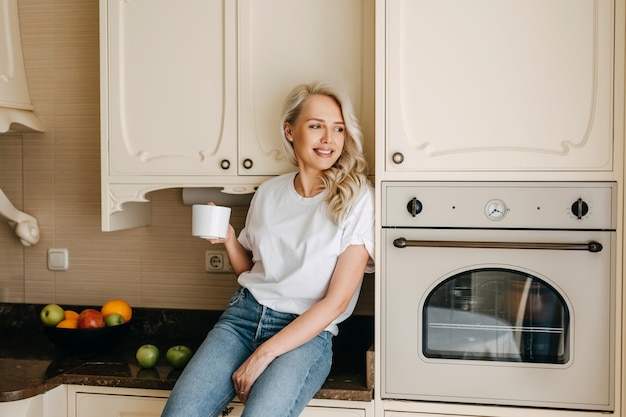 Donna in cucina con una tazza di caffè al mattino