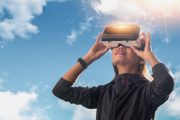 Donna in cuffia avricolare di VR che cerca nella realtà virtuale. La realtà virtuale è una tecnologia informatica che simula una presenza fisica e consente all'utente di interagire con l'ambiente.