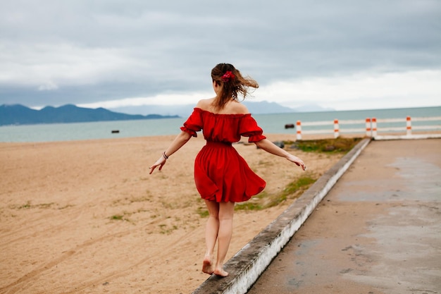 Donna in equilibrio sulla strada. Femmina con vento tra i capelli sulla spiaggia in equilibrio.