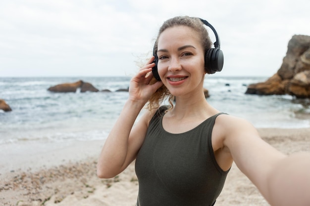 Donna in forma caucasica attraente che ascolta la musica con le cuffie sulla spiaggia