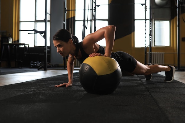 Donna in forma e muscolosa che si esercita con la palla medica in palestra.