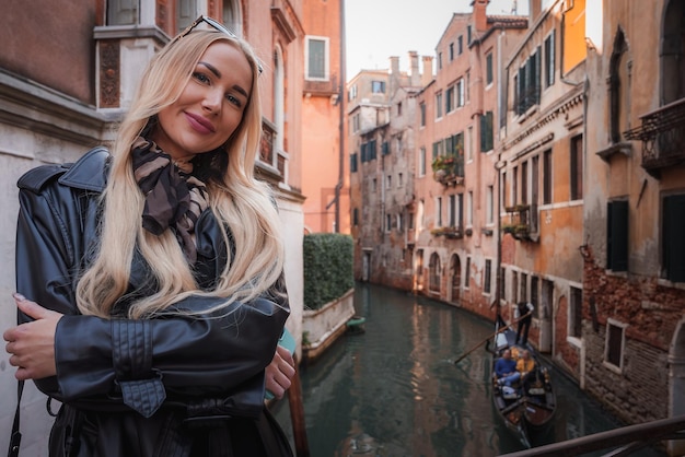 Donna in giacca di pelle in posa casuale sul ponte del canale di Venezia, in Italia