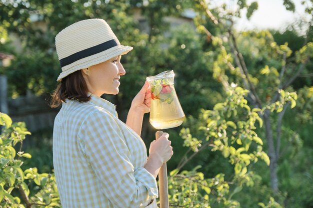 Donna in giardino con bevanda a base di erbe fatta in casa naturale