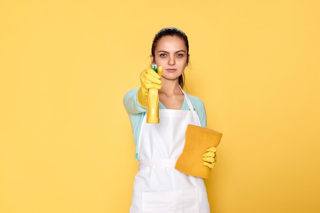 Donna in guanti e grembiule più pulito con spugna e spruzzatore detergente