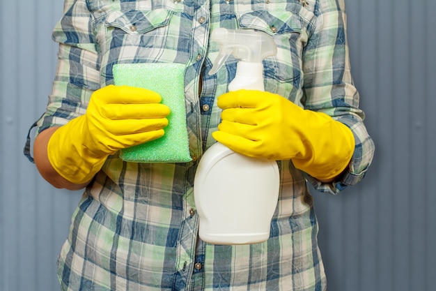 Donna in guanti protettivi con bottiglia di liquido detergente