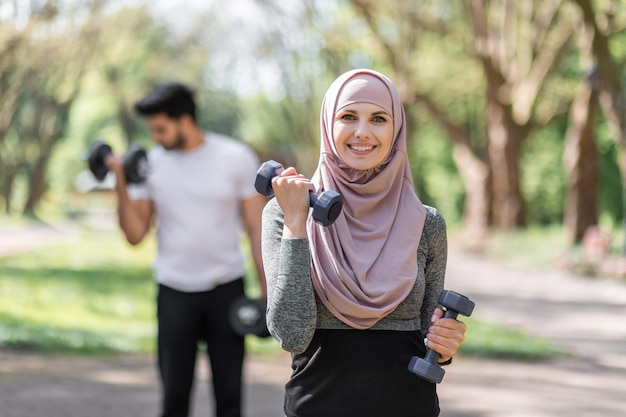 Donna in hijab e ragazzo musulmano allenamento con manubri