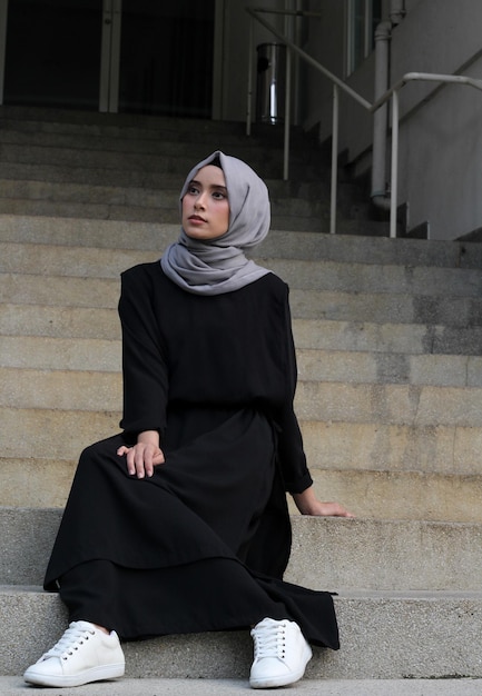 Donna in hijab seduta sui gradini