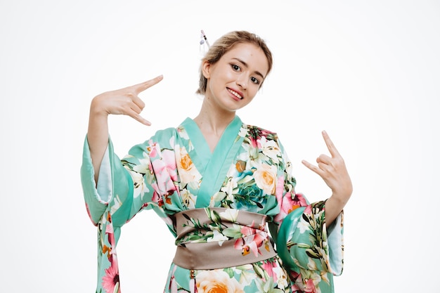 Donna in kimono giapponese tradizionale felice e gioiosa che mostra simboli rock su bianco