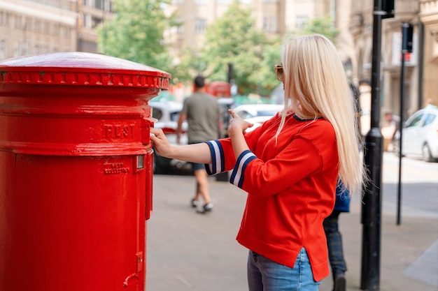 Donna in lettere rosse di invio brevi nella casella di posta rossa in Inghilterra
