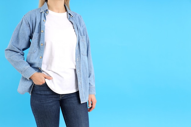 Donna in maglietta bianca e camicia di jeans su sfondo blu