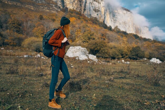 Donna in maglione allunga la mano alla telecamera all'aperto in autunno modello di turismo di viaggio