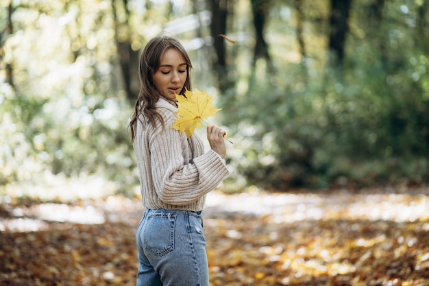 Donna in maglione caldo che cammina nel parco autunnale