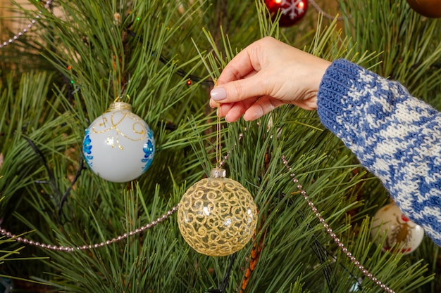 Donna in maglione che decora l'albero di Natale con le palle del giocattolo