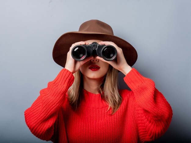 Donna in maglione rosso e cappello con binocolo