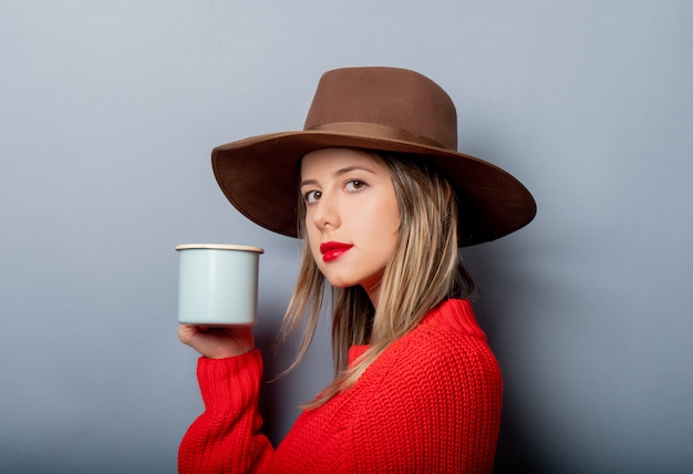Donna in maglione rosso e cappello con la tazza di caffè
